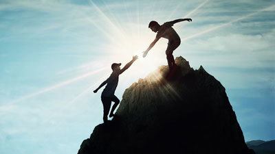 Extending a Hand to Help a Comrade Climb The Mountain Together Helping others ascend to new heights so they can share in the success of a job well done.